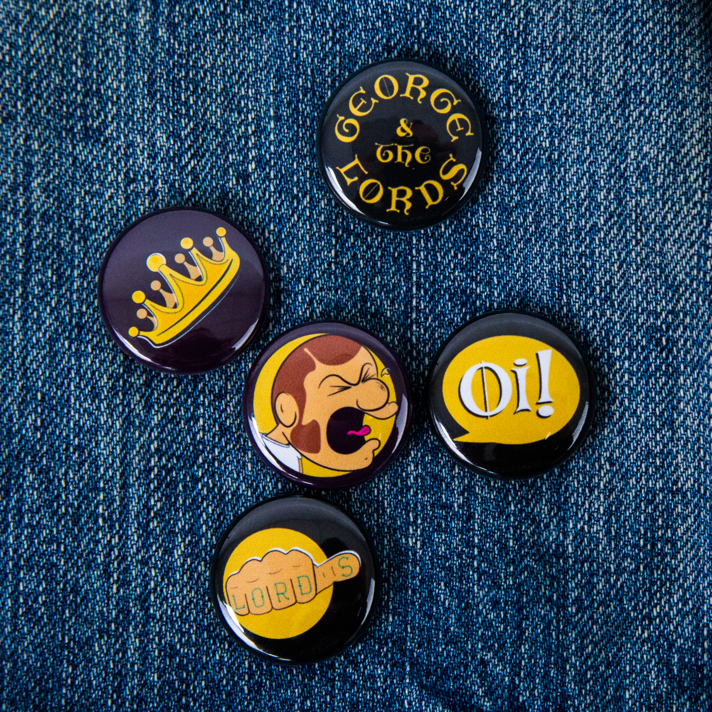 Five George & the Lords pins on a denim jacket